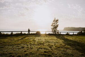 a person standing on a grass covered hill overlooking a body of water